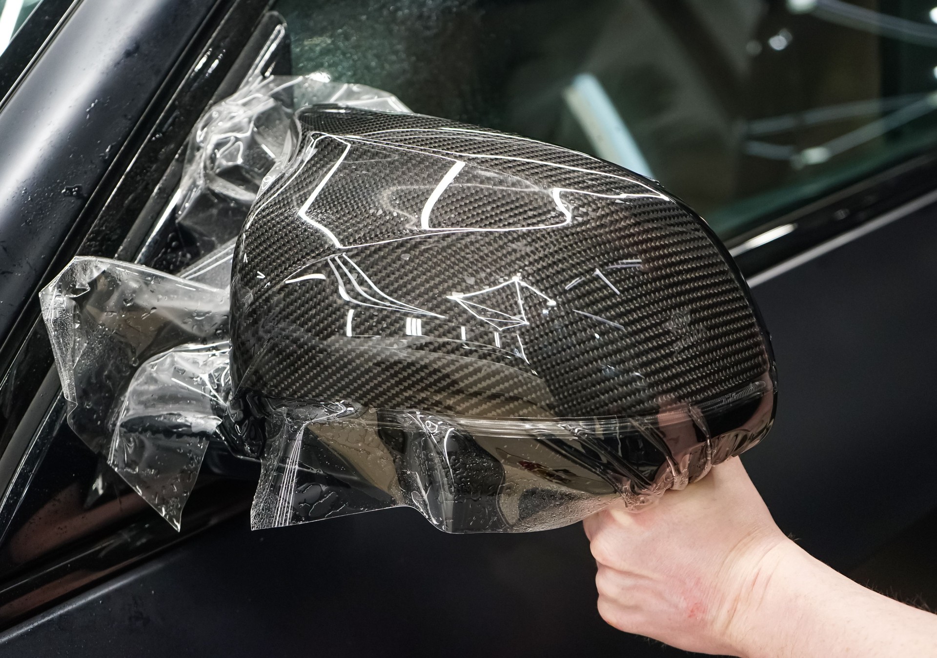 The process of installing PPF on the side mirror. Car wrapping close-up. Car wrapping. A car wrapping specialist applies a polyurethane film to the car. Selective focus. PPF protective film.