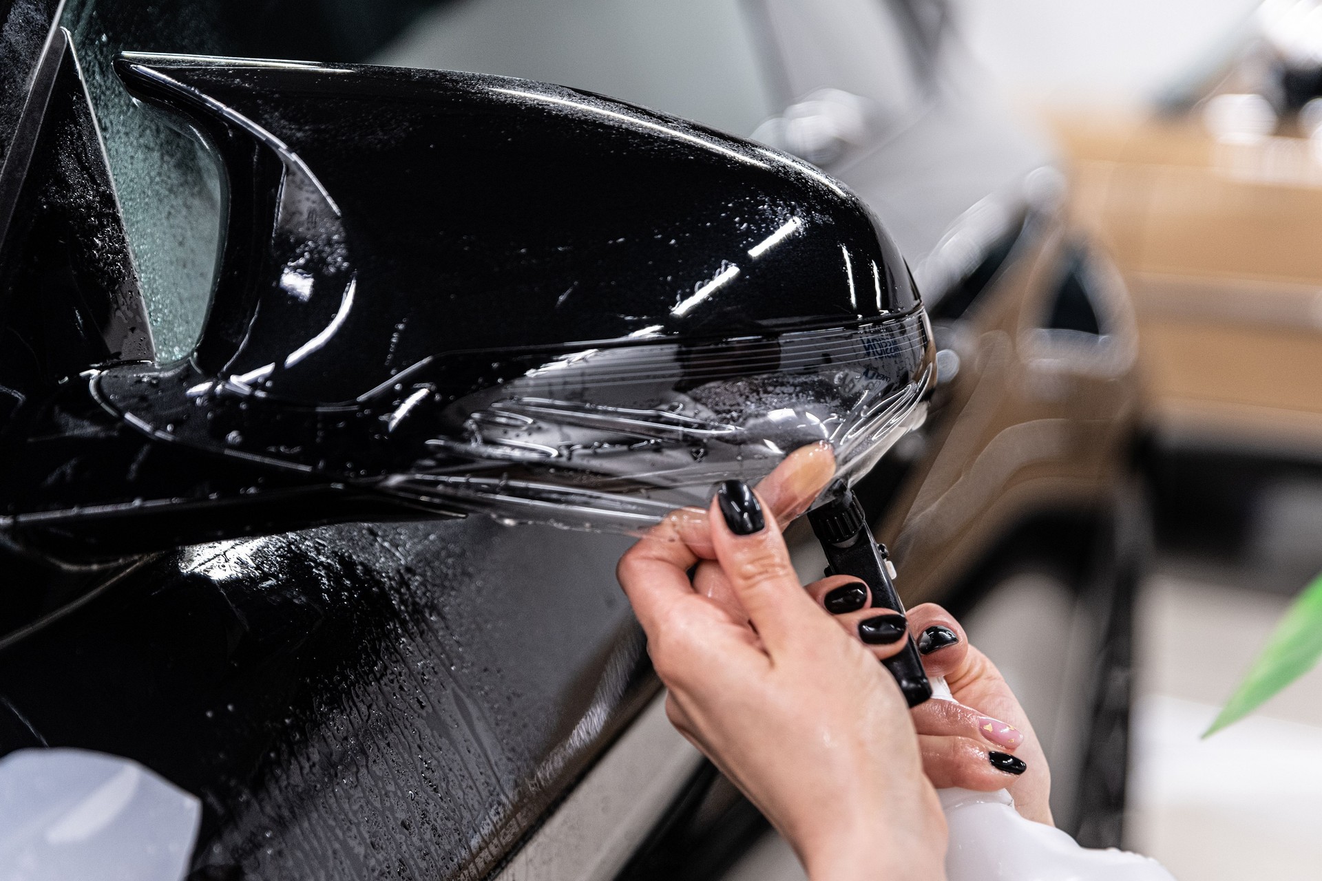 Car detailing technician applying transparent ppf foil